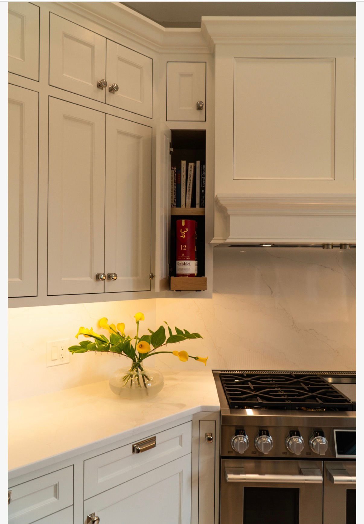 The finished kitchen, white cabinetry and range with fresh tulips