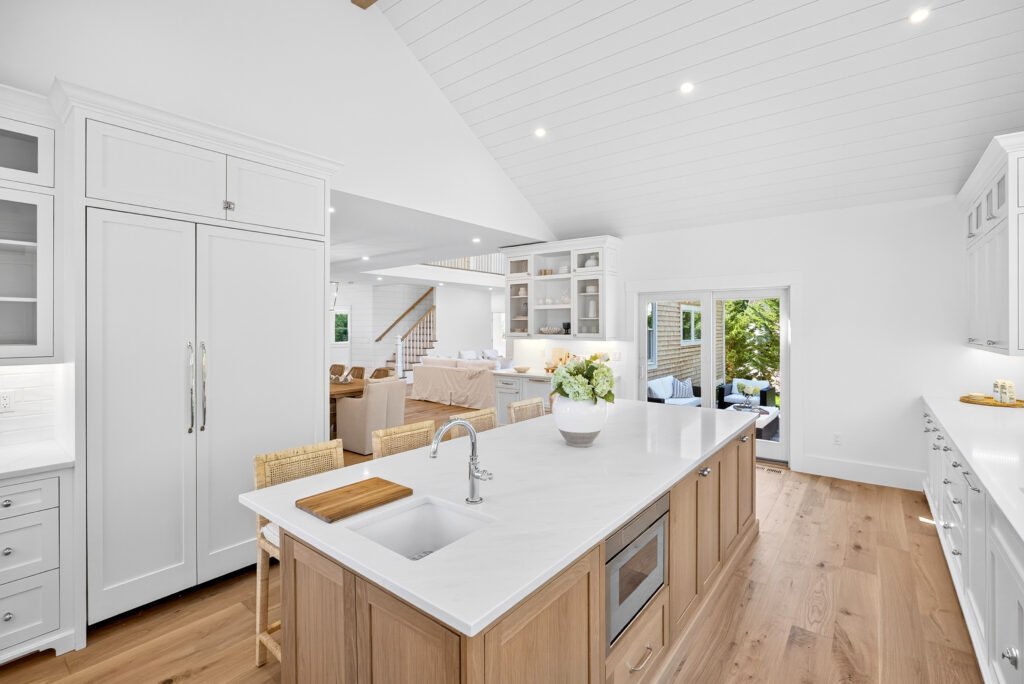 Open white kitchen with oak island and shiplap vaulted ceiling