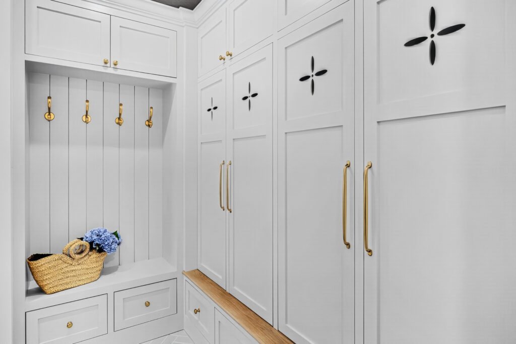 Custom mudroom with white lockers, oak bench and brass hooks