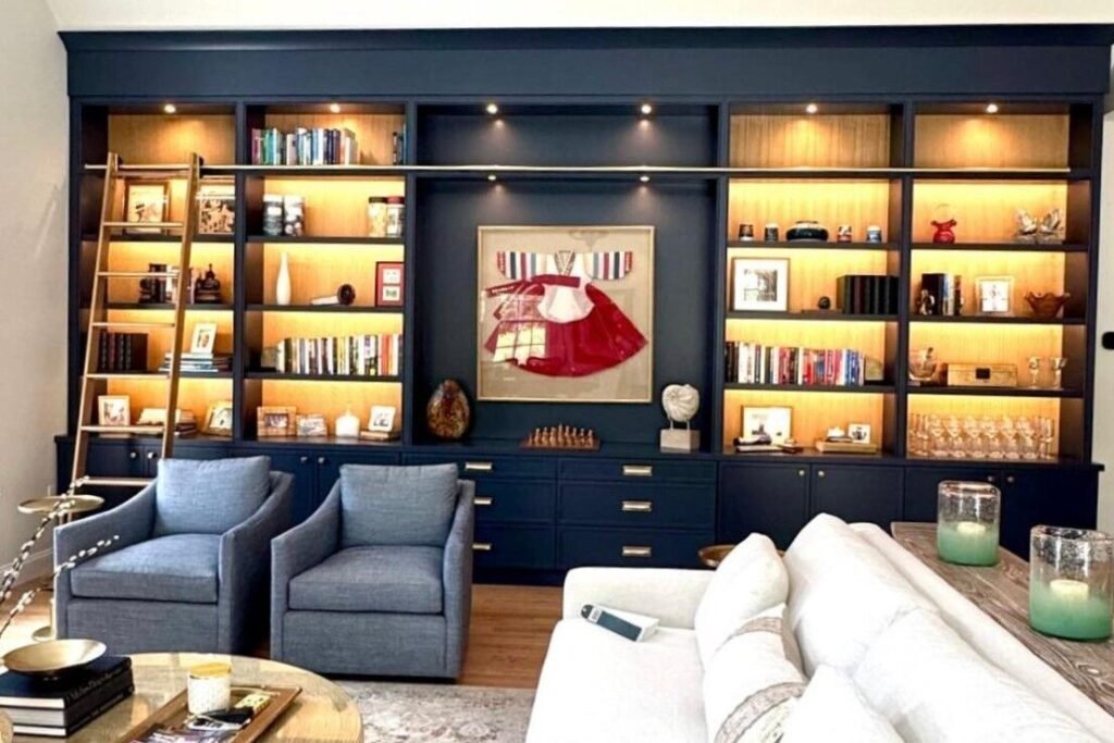 Navy floor-to-ceiling home library with lit shelving and rolling ladder